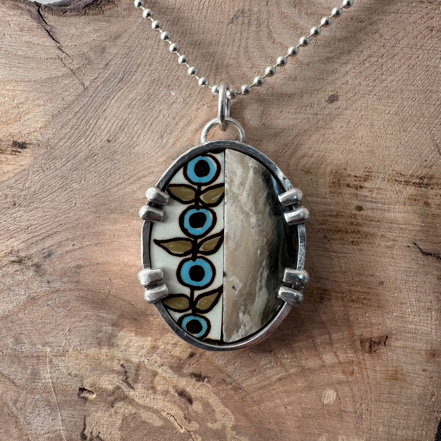 1.625"x1.25" oval recycled sterling silver mosaic pendant with a flower print ceramic and polished olive green and silvery beige petrified wood inside