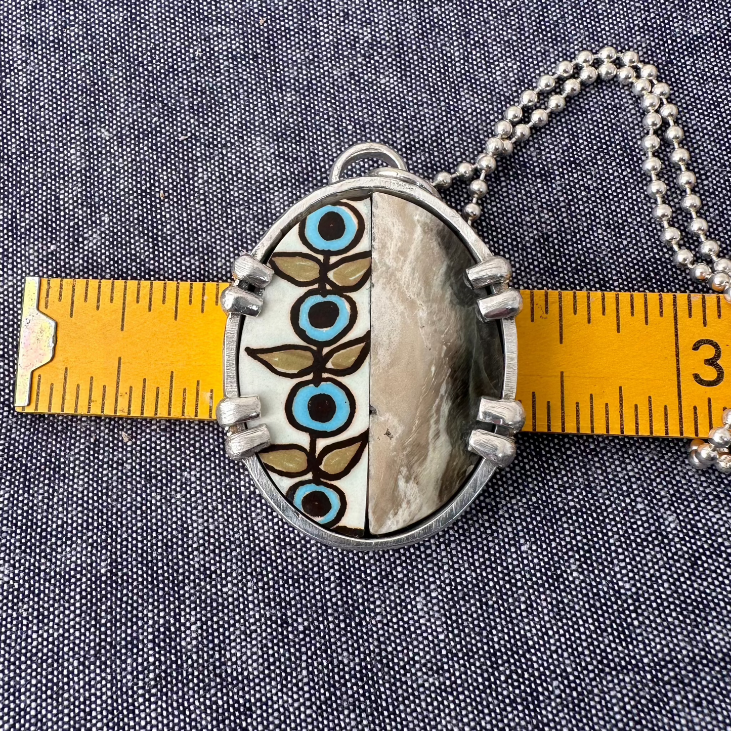 1.625"x1.25" oval recycled sterling silver mosaic pendant with a flower print ceramic and polished olive green and silvery beige petrified wood inside